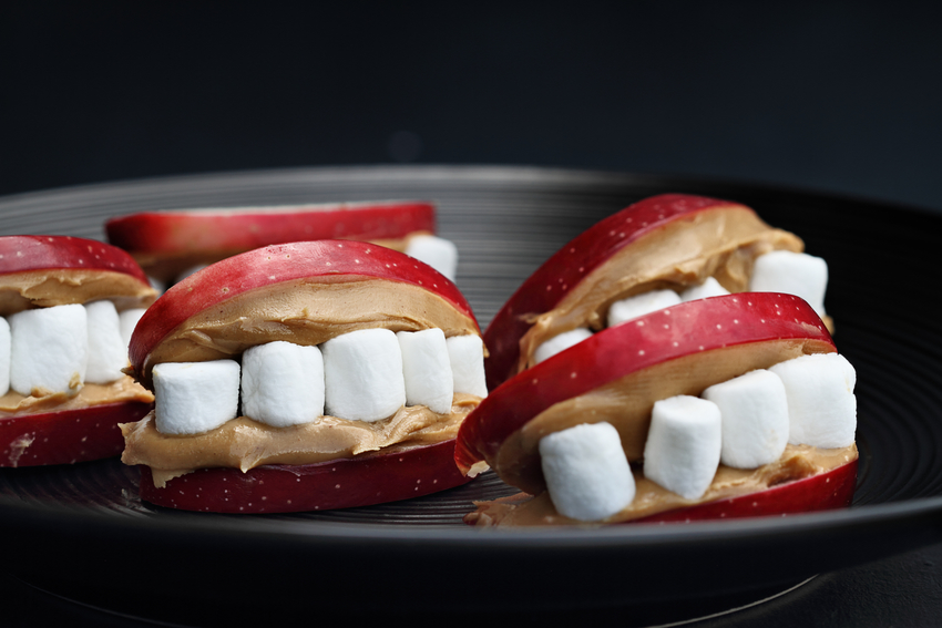 Apple slices are covered in peanut butter and filled with mini marshmallows to look like a monster's smile.